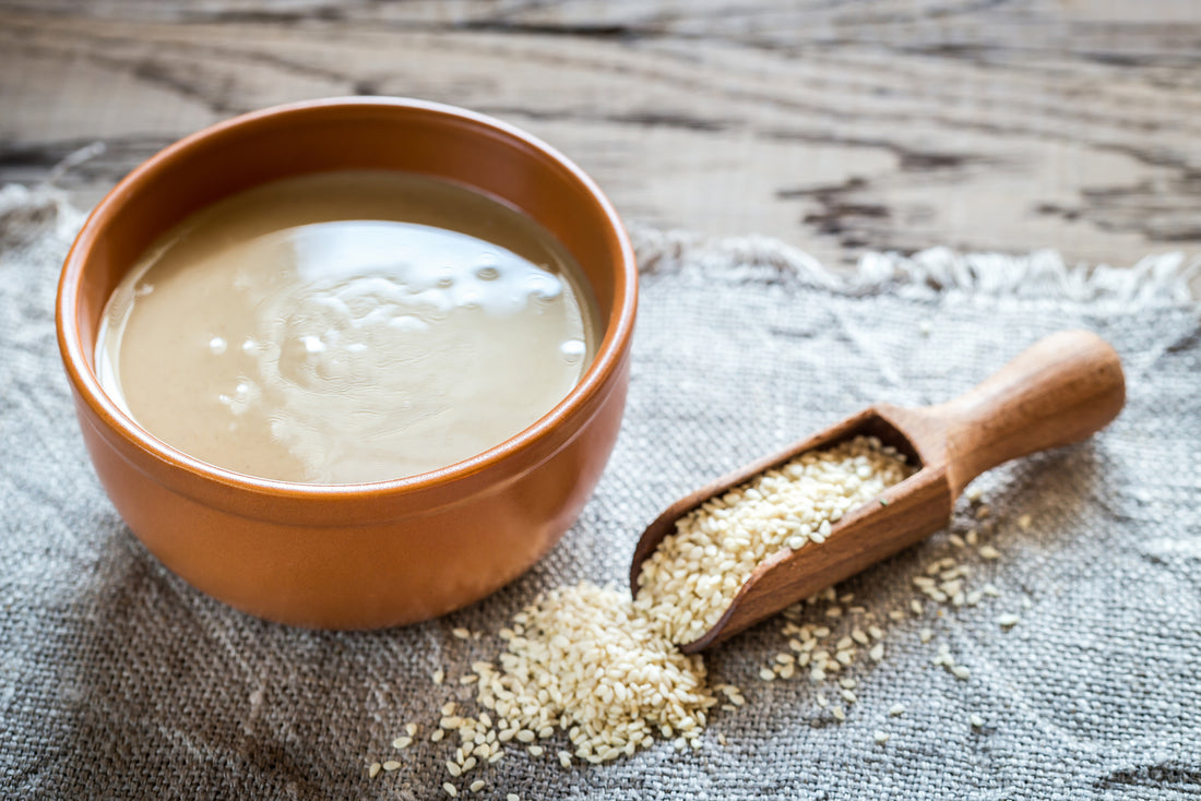 FUN Sesames Tahini Paste | Sesame seeds rest delicately on a wooden scoop, while a bowl holds creamy sesame paste, showcasing the essence of this versatile ingredient.